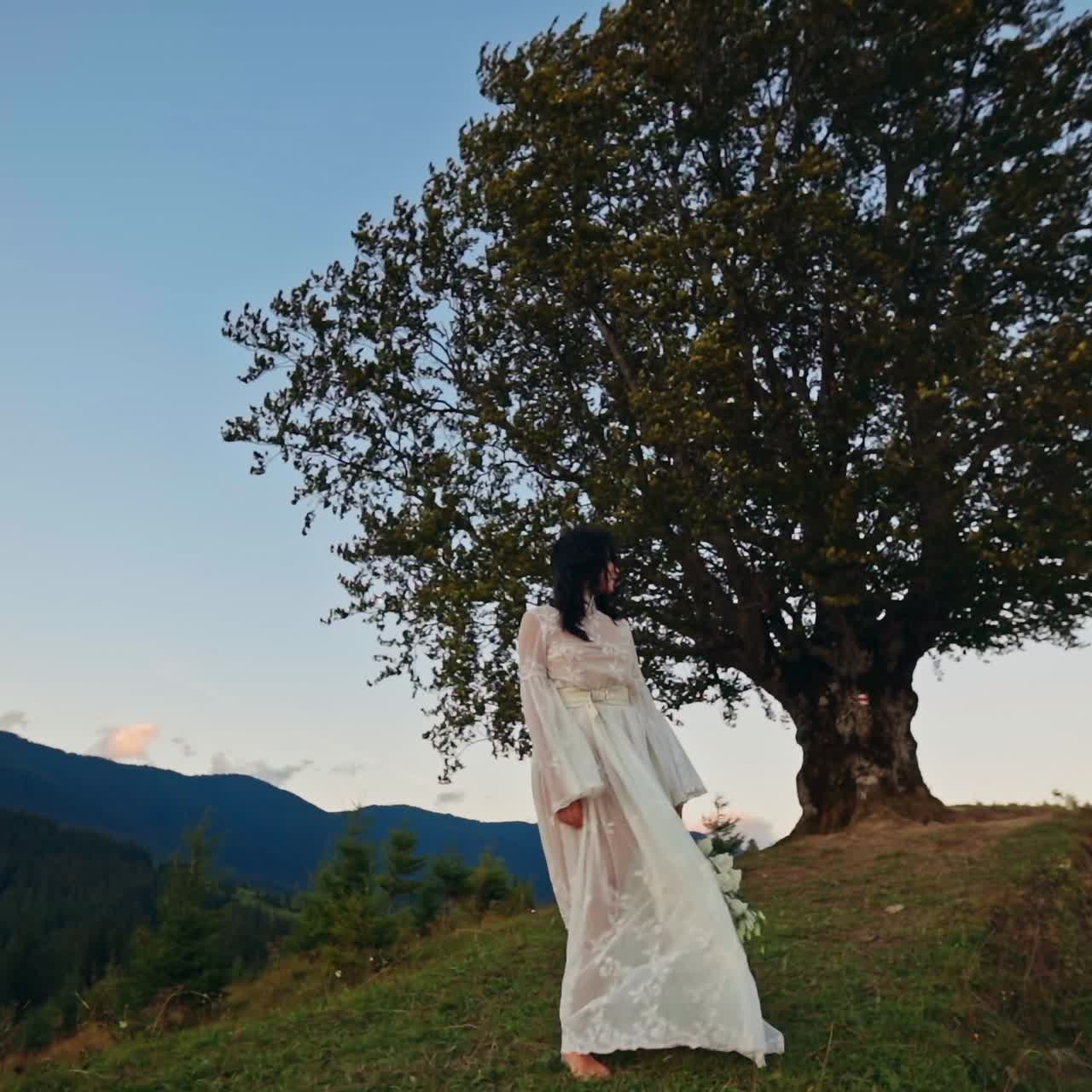 Young woman in white dress walks on the mountains. Attractive pretty lady posing in nature