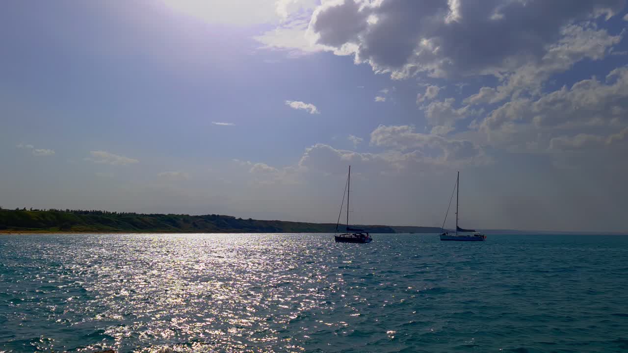 reflejos de la luz del sol sobre el agua de mar y siluetas de barcos anclados