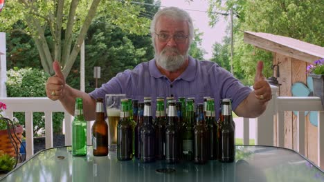 an older man with a beard sits on a patio table surrounded by empty bottles. he enjoys a craft beer while relaxed under the warm summer sun, creating a carefree atmosphere