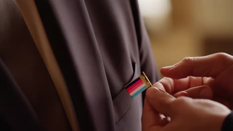 a person attaching a lapel pin to a uniform or suit
