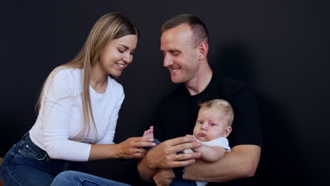 loving young couple with their adorable baby. mom kisses tiny foot of her baby and man kisses his wife on the head.