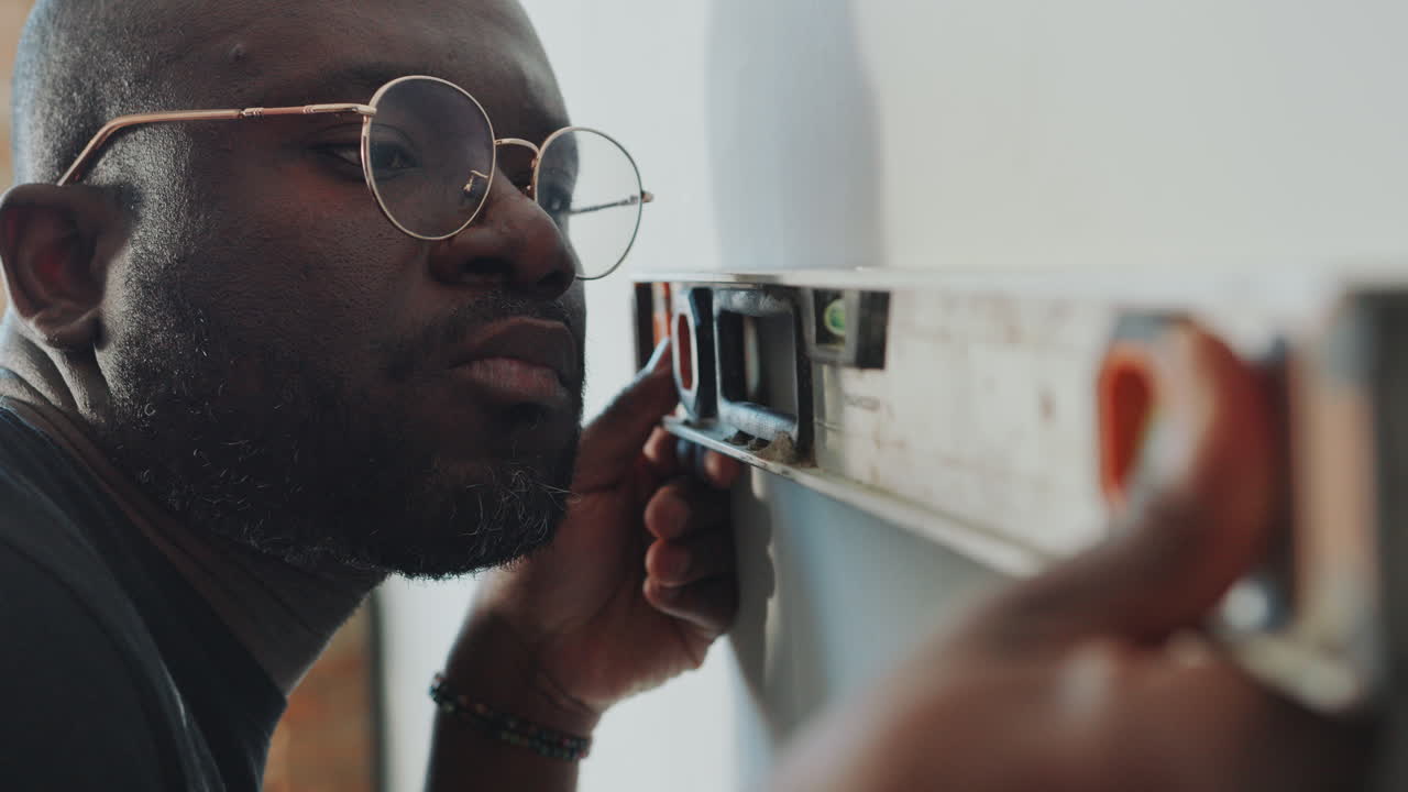 Black Man Checking Wall Surface with Spirit Level during Home Renovation