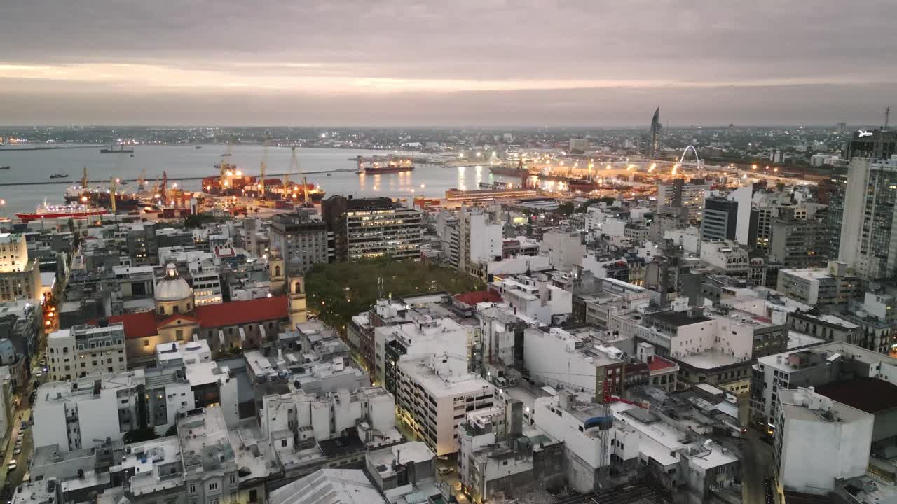 드론 이 몬테비데오 위 에서 날아다니며 우루과이 의 도시 는 하늘을  ⁇ 는 건물 과 항구 가 밤 에 조명 된다