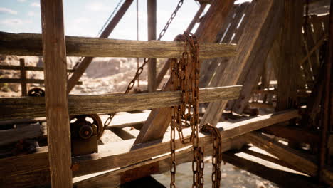 rusty chains hanging from a wooden structure over water in bright sunlight