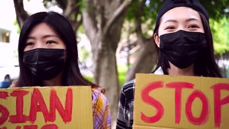 asian women with posters during protest in city