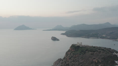 Drone-shot-of-ancient-ruins-in-Greece-with-sun-setting-in-background