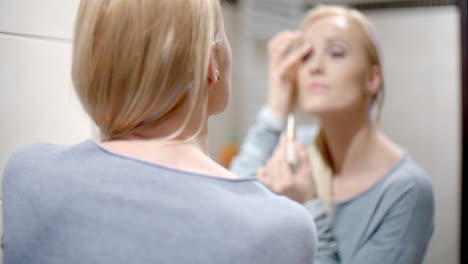 happy woman putting make up in front a mirror