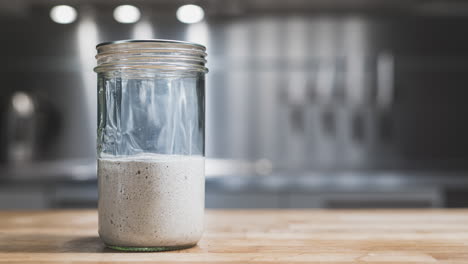 mezcla de harina y agua que sube en un frasco de vidrio durante el proceso de fermentación para el iniciador de masa fermentada - lapso de tiempo