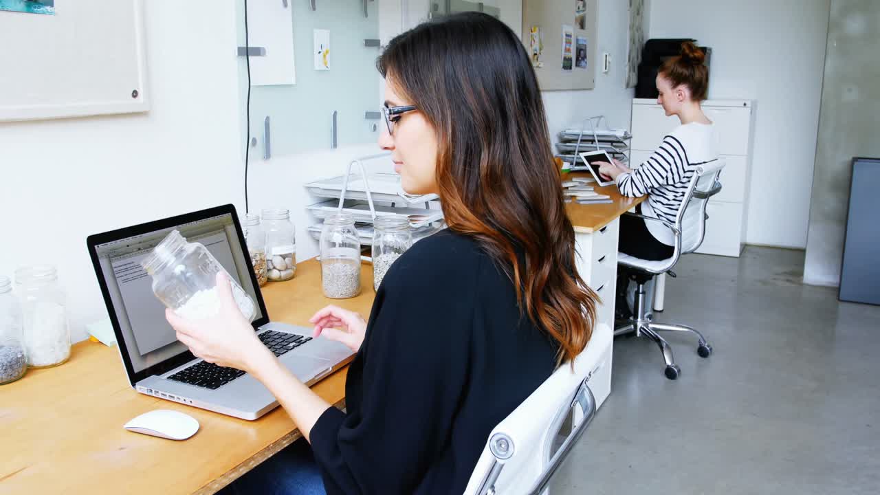 ejecutivo de negocios usando portátil mientras sostiene un frasco de guijarros