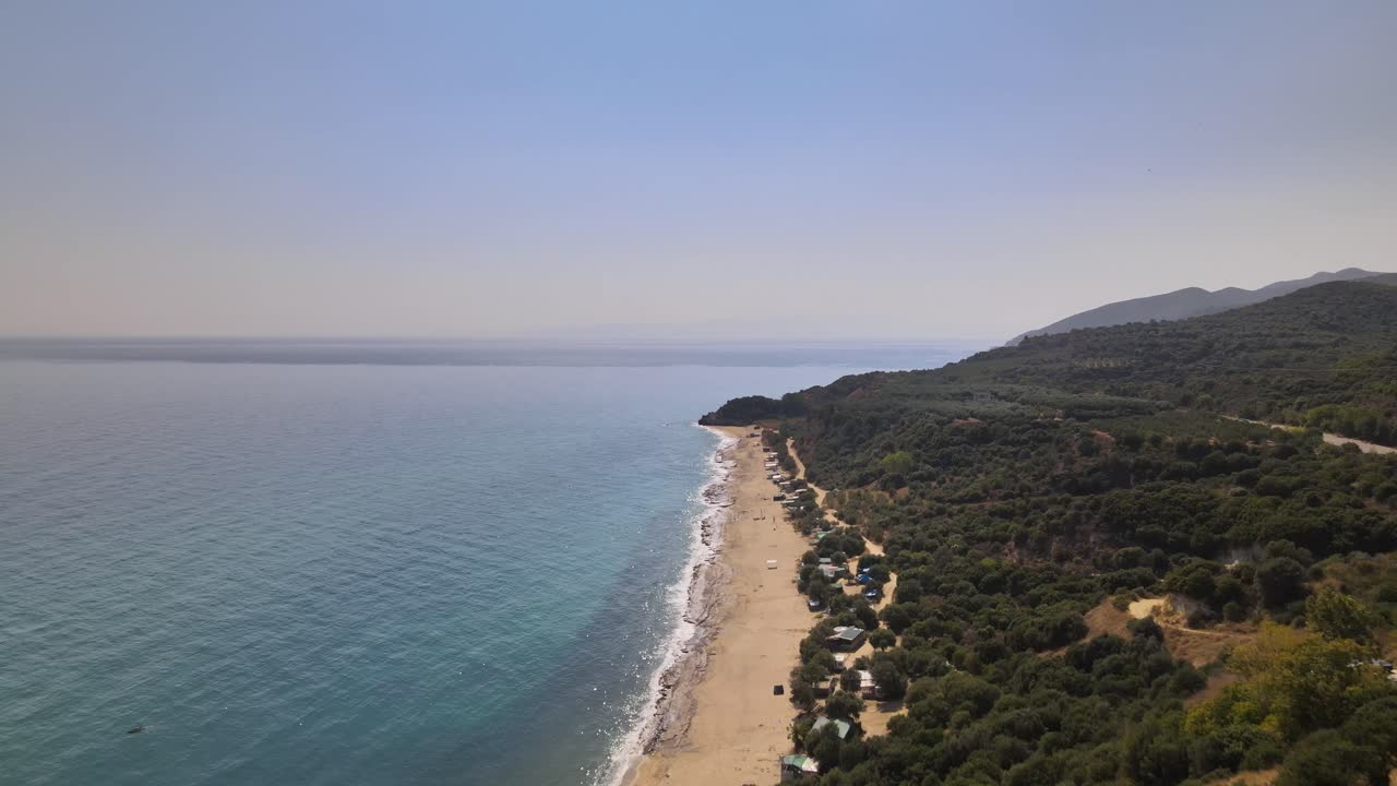 Drone clip moving forward over ancient tower ruins and a blue beach in Kavala, Greece