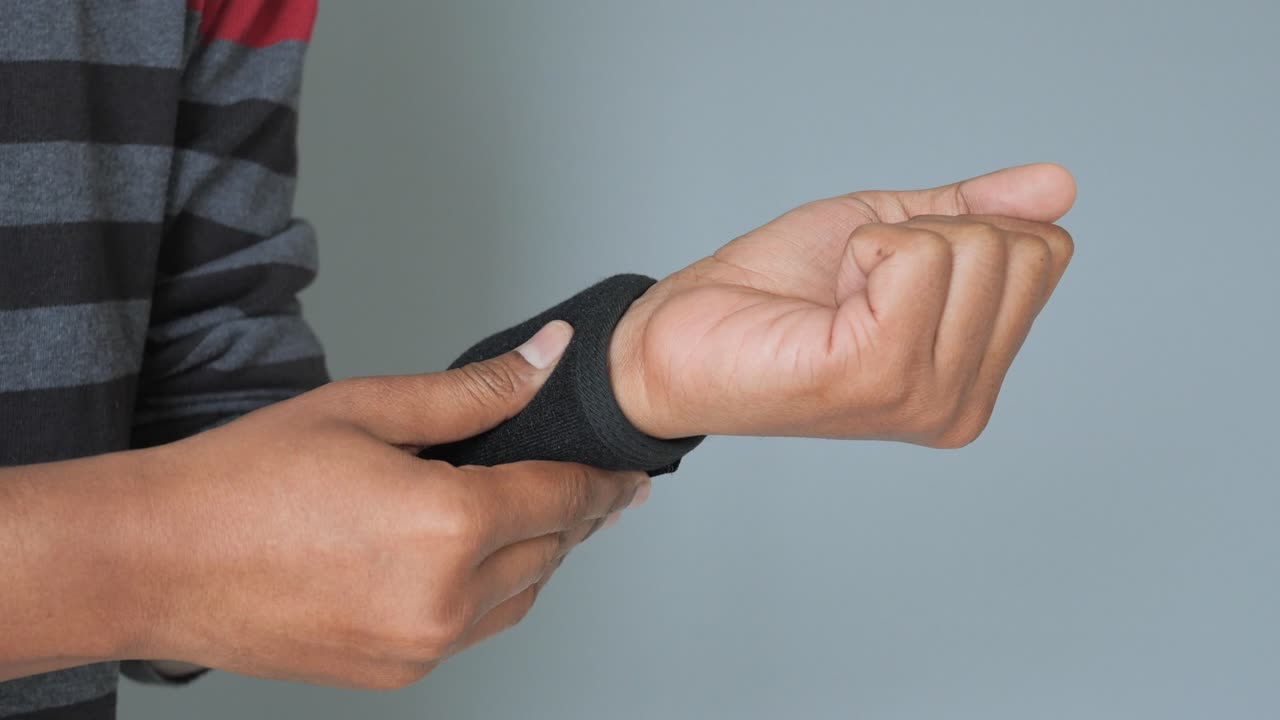 Uomo che si sistema un tutore da polso nero sulla mano.