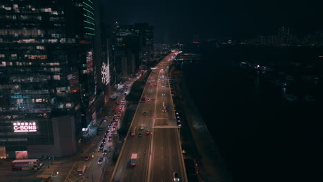 Disparo-Aéreo-Hacia-Atrás-Sobre-Una-Concurrida-Carretera-En-El-Distrito-De-Kwun-Tong-Por-La-Noche-En-Hong-Kong