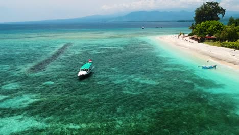 pequeño barco de transporte rodeado de aguas turquesas cristalinas y arrecifes de coral frente a la costa de la isla de gili air en indonesia