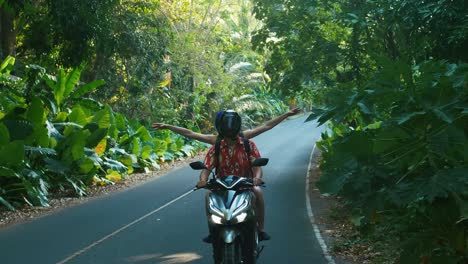 young beautiful tourist couple rides the jungle on a scooter wearing helmets. travel, freedom, happiness, vacation, honeymoon concept.