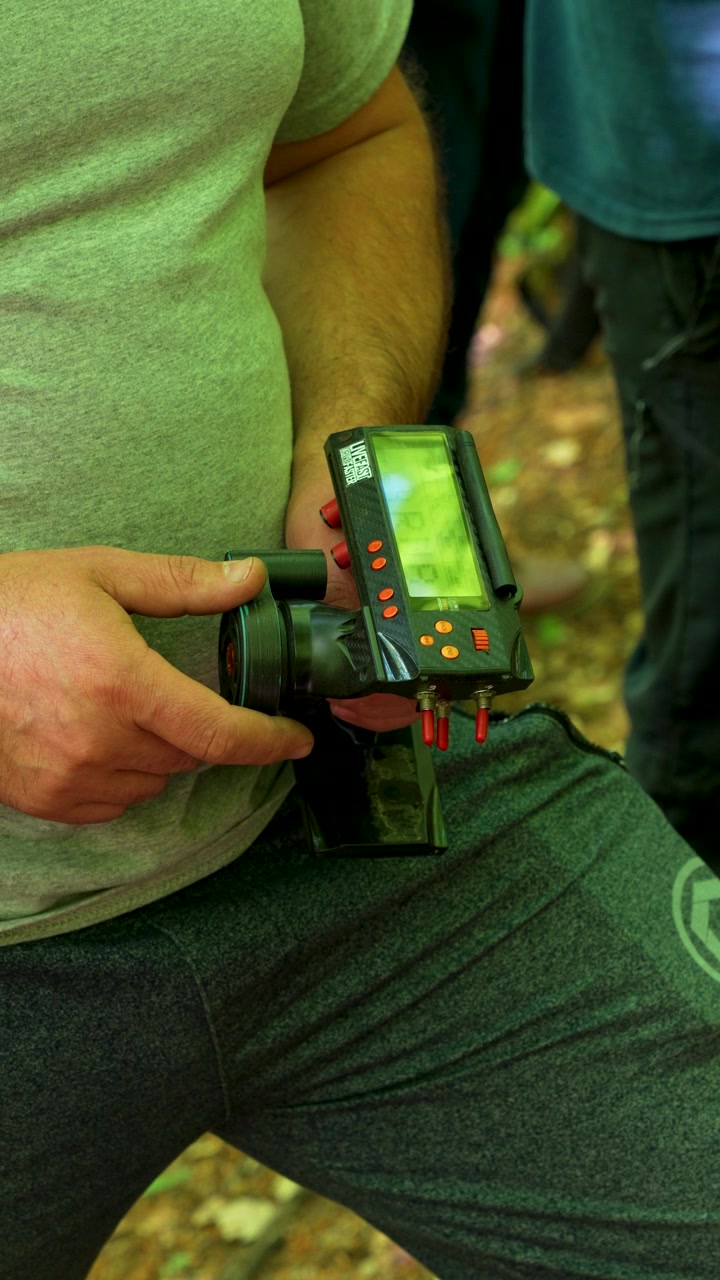 Un primo piano di una persona che tiene un controller trasmettitore RC digitale a impugnatura a pistola con interruttori a levetta rossi personalizzati