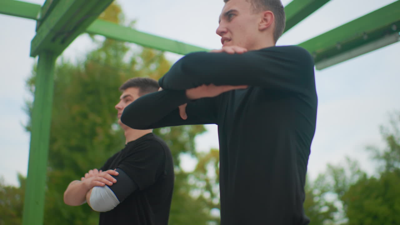 focused white man leading arm stretches, instructor role shifts between coach and mentor, dynamic motion under green canopy, cadence driven warmup, determined breathing and crisp posture across frames