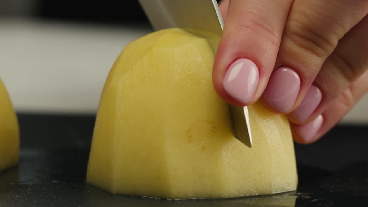 Woman cutting potato on table in kitchen. High quality 4k footage