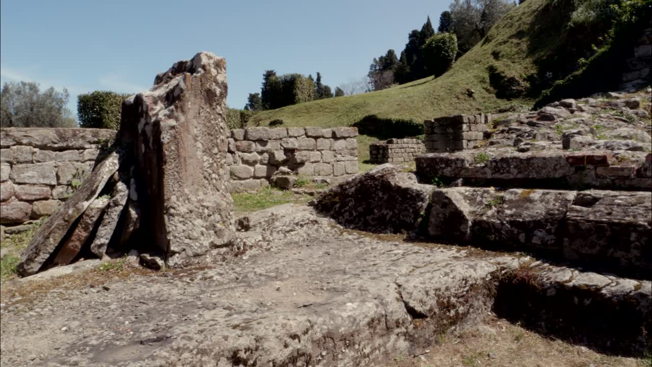 Panoramica lenta di antiche rovine in pietra su un pendio erboso