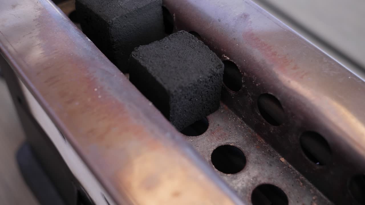 검은 석탄을 전기 물 담뱃대 숯 라이터에 넣는 흰 장갑을 낀 남자