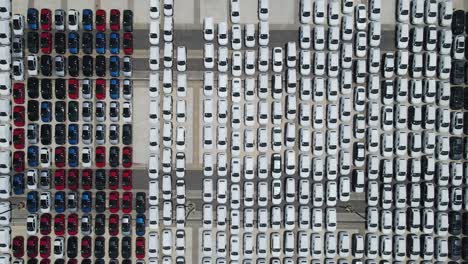 camera ascends over a vast lot filled with neatly parked cars in white, red, black, and blue