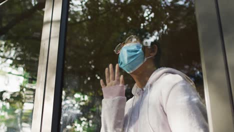 asian girl wearing face mask and looking through window