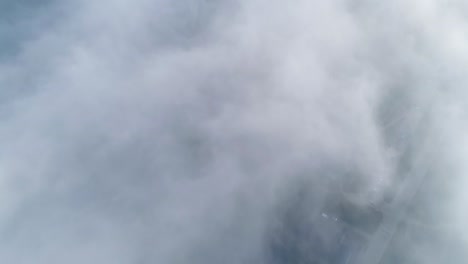 vuelo sobre nubes brumosas a la luz del sol de la mañana con poca gloria y paisaje urbano bajo las nubes
