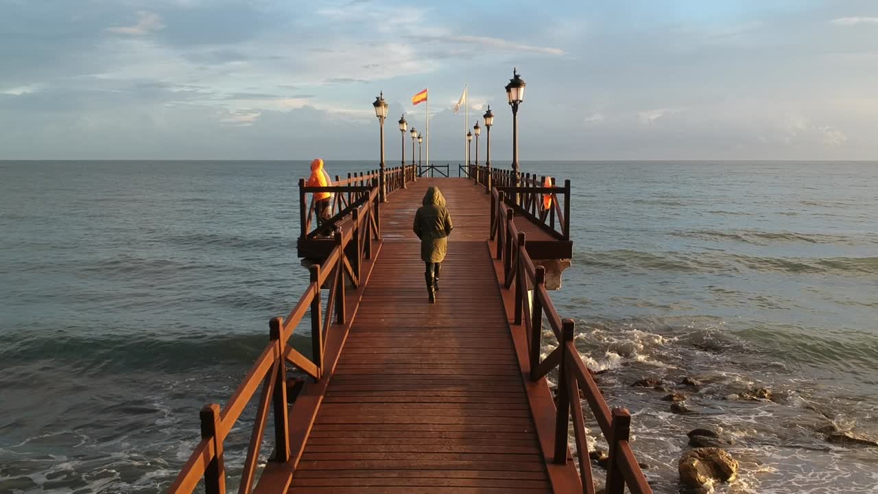 embarcadero de madera en el mar mediterráneo con gente caminando sobre él