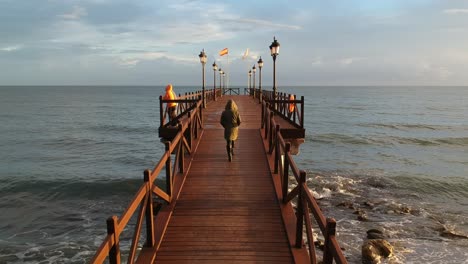 embarcadero de madera en el mar mediterráneo con gente caminando sobre él