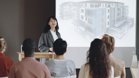 Mujer-Asiática-Presentando-Proyecto-Arquitectónico-En-Conferencia