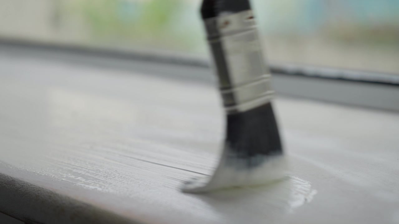Decorating window with gloss paint in domestic house. Close up slow motion.