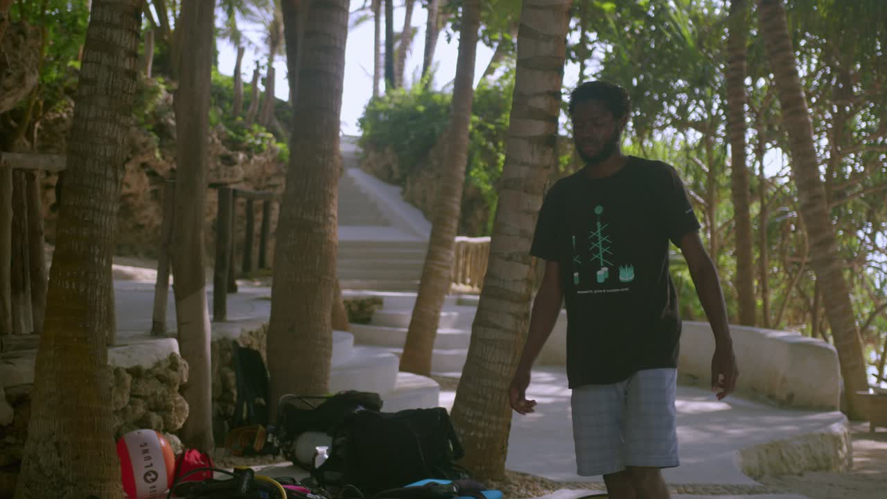 Uomo africano che cammina nel resort dopo un'immersione subacquea in Kenya.