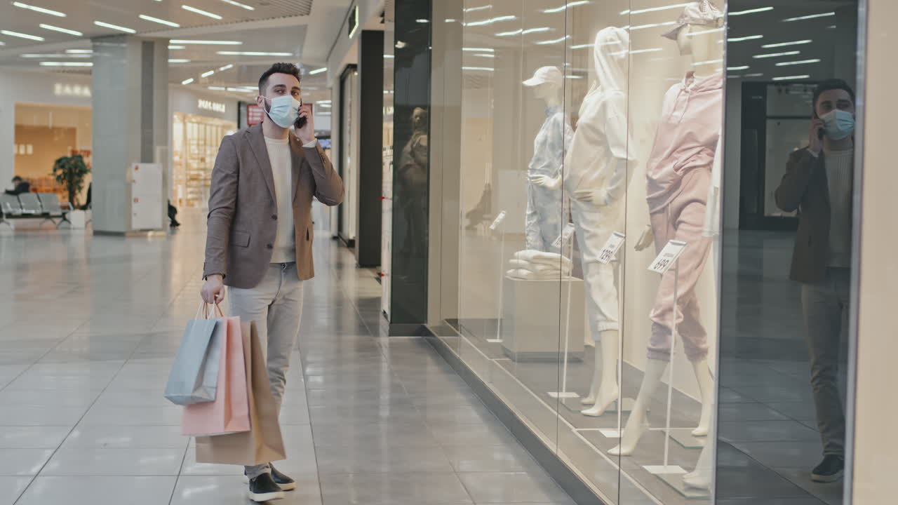 Handsome Man Having Phone Call Near Window Display In Shopping Mall