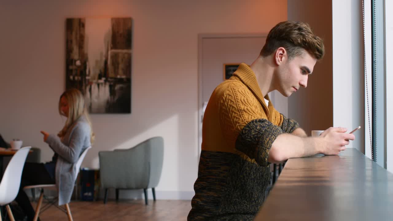 vista lateral de un joven usando un teléfono móvil en el café 4k