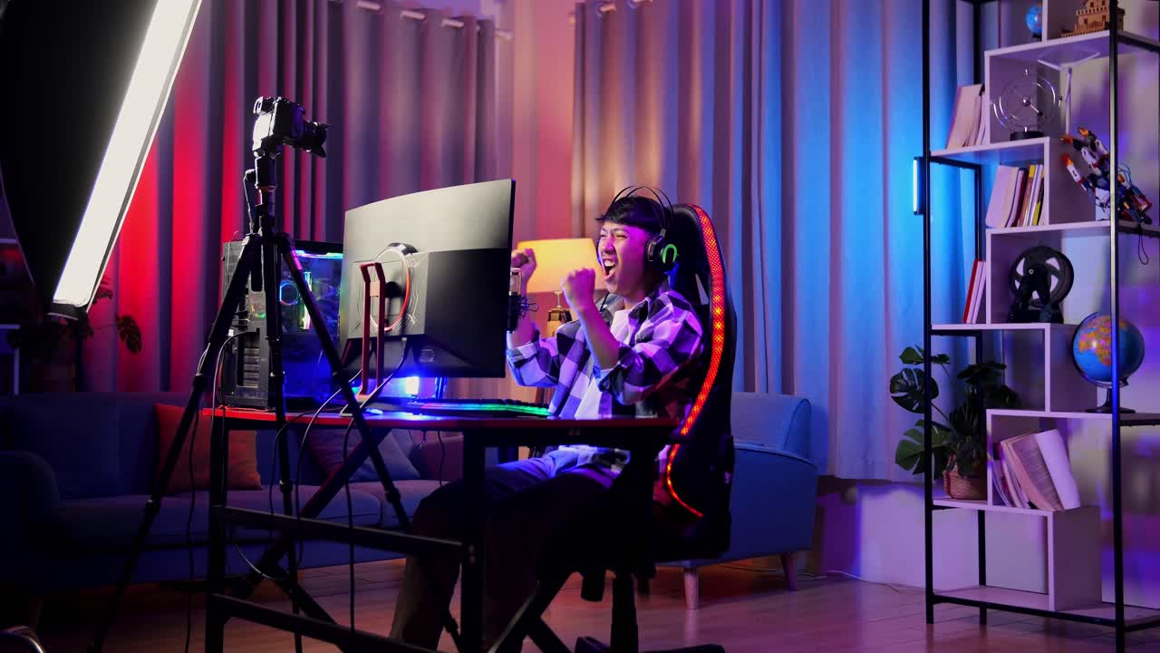 asian boy streamer gritando gol celebrando el juego ganador a través de la red en la computadora personal. videojuego de transmisión en vivo, escritorio iluminado por luz de tira de led rgb