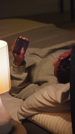 woman using phone in bed at night