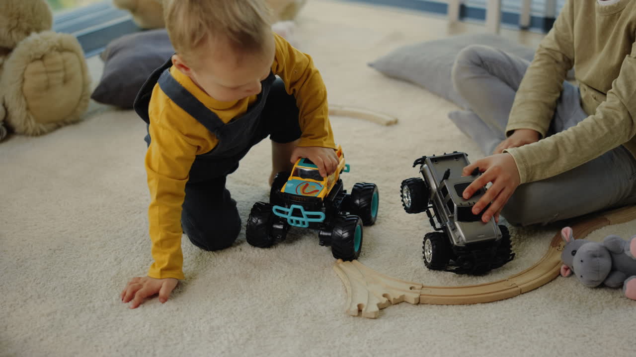 바닥에 장난감 트럭과 놀고 있는 재미있는 소년. 집 안에서 시간을 보내는 형제자매