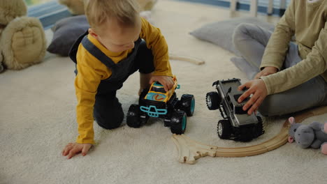 niño divertido jugando con un camión de juguete en el suelo. hermanos pasando tiempo en el interior de la casa