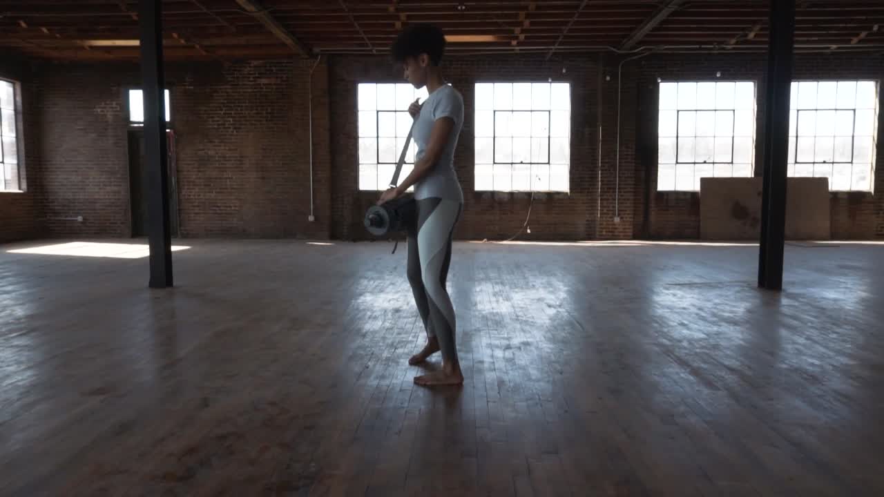 un'attrice di fitness nera mostra un tappetino da yoga in un magazzino