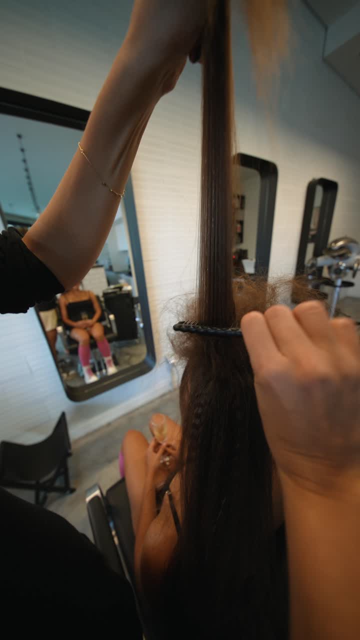 Hair Stylist Combing Woman's Hair in a Beauty Salon