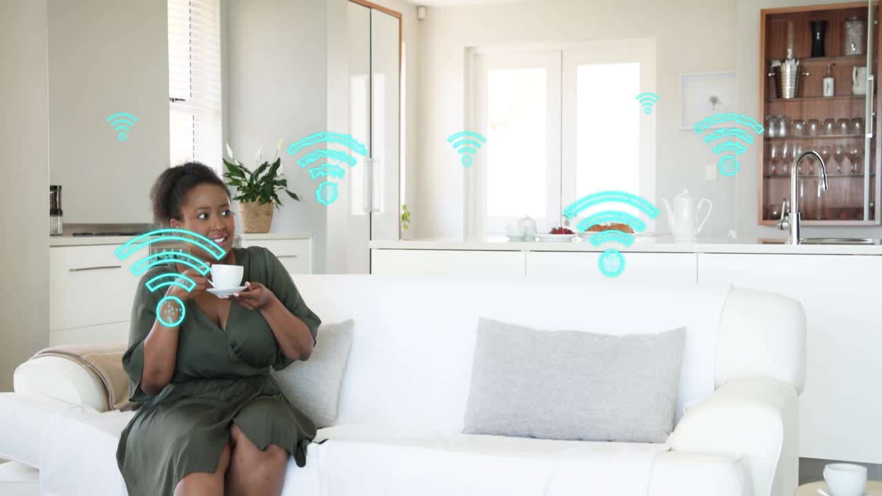 Two women sitting on sofa talking, causing tech Wi?Fi icons, right leaving, left sipping smiling