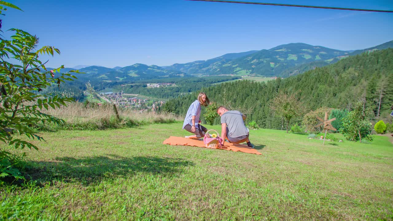 Young romantic couple walk on grass with picnic basket, Vuzenica