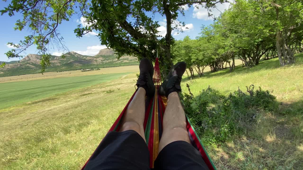los pies balanceándose en una hamaca al aire libre en el bosque - pov