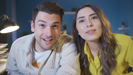 Young-married-couple-looking-at-camera-with-amazement-at-their-home-and-waving.