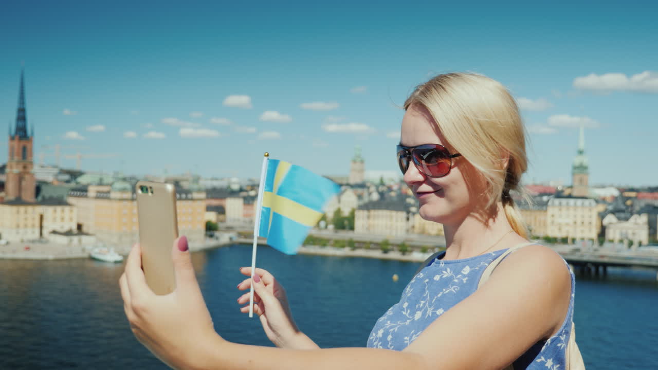 스웨덴 국기를 든 행복한 관광객이 스톡홀름을 배경으로 자신의 사진을 찍는다'