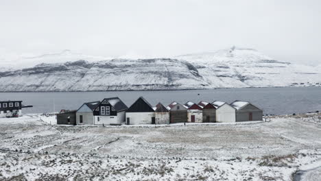 Islas-Feroe,-Vista-Aérea-4k-De-Los-Cobertizos-Para-Botes-De-Hósvík-Mientras-Retrocedemos-Lentamente-Para-Revelar-Más-Del-Paisaje-Circundante