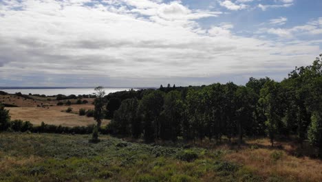 Aerial-view-of-the-coastline-of-Sejerøbugten-with-hills,-fields-and-ocean