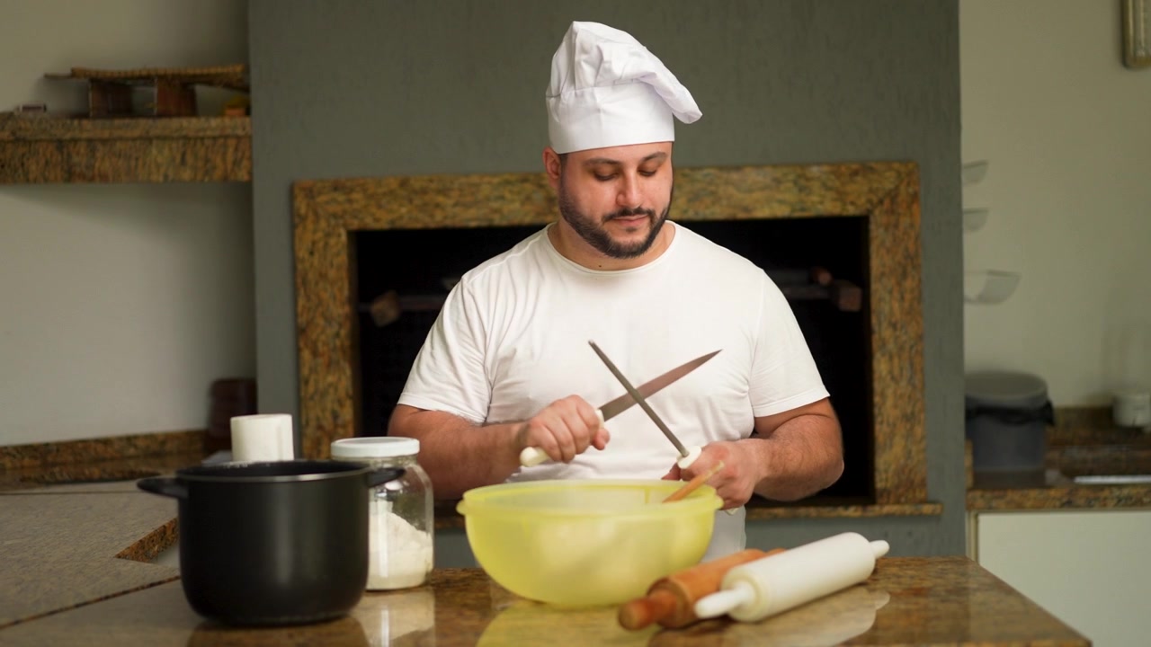 Uno chef professionista affila i suoi coltelli da cucina con un acciaino