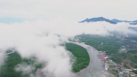 Flying-Above-the-Clouds-with-a-Fishing-Village-Below-at-Lang-Thung-Nang-Dam-River-at-Khura-Buri-District-Province,-Thailand