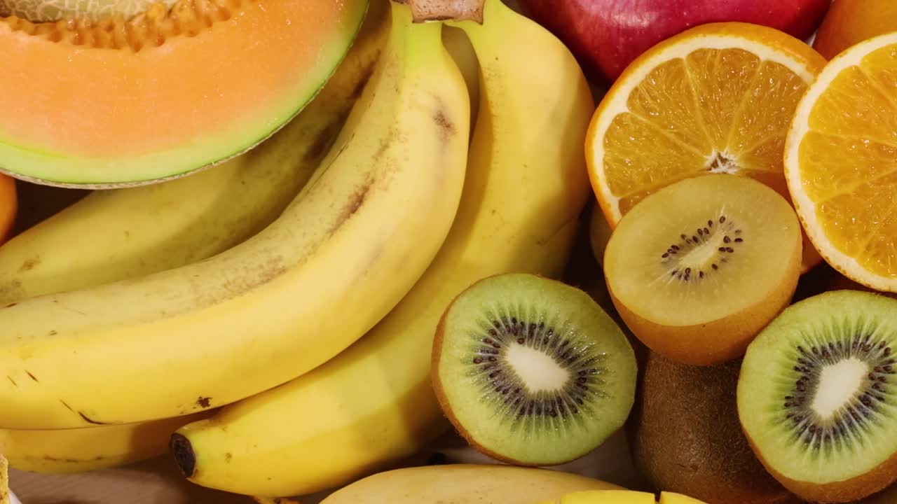 A colorful arrangement featuring bananas, kiwis, pomegranates, and other fresh fruits in a vibrant display.