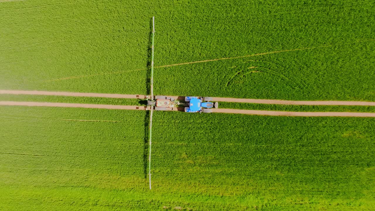 Top down drone view of tractor spraying crops in sunny Latvia with sharp lines